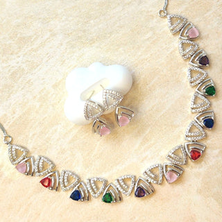Necklace and earrings with gemstones on a beige surface
