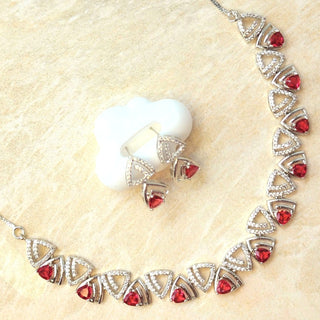 Silver necklace with red gemstones on a beige surface