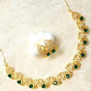 Gold necklace with green gemstones on a beige background