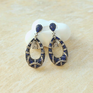 Pair of blue and silver earrings on a beige background