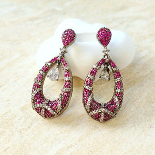 Pair of pink gemstone earrings on a beige surface