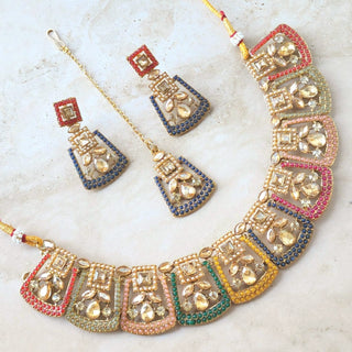 Colorful polki necklace, maang tikka and earrings set on a textured surface