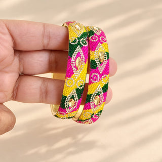 Poppy pink yellow green Indian artificial kada bangles close-up held in hand