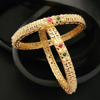 2 Gold bracelet bangles with gemstones on a black background