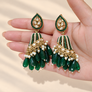 Adeline dark green polki jhumka earrings held in hand showing green and white beaded dome and faceted emerald green drops