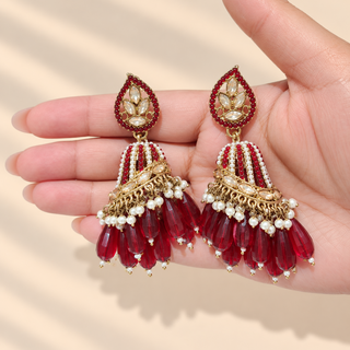 Adeline maroon red polki jhumka earrings held in hand showing teardrop stud and red white beaded jhumka domes