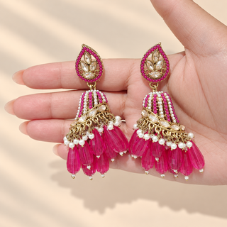 Adeline rani pink Indian polki jhumka earrings held in hand showing pink and white beaded dome and drop tassels