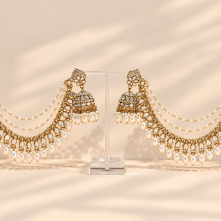 Adeline white mirror baahubali jhumka earrings with gold finish pearl drops and ear chains on acrylic display