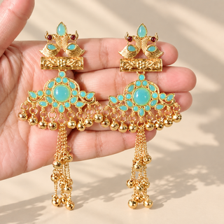 Claudine light blue Kashmiri earrings in gold finish with turquoise blue stones and hanging bells held in hand