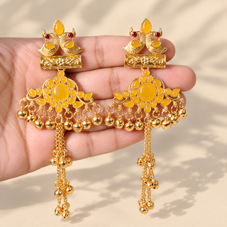 Claudine yellow Kashmiri earrings in bright gold finish with bird motifs and ghungroo chain tassels held in hand