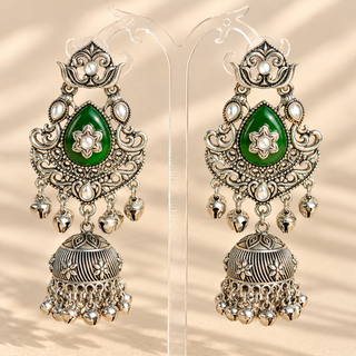 Cressida dark green German silver oxidised kundan jhumka earrings 8.5 cm with emerald green teardrop stones and ghungroo bells on display stand