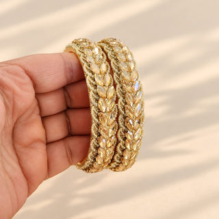 Cressida pair of gold Indian statement bangles with champagne marquise rhinestone leaves held in hand