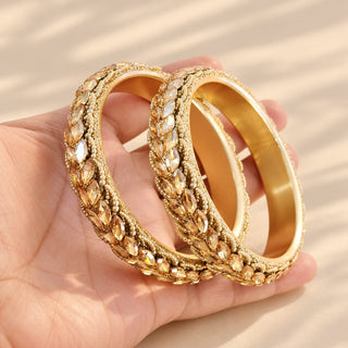 Cressida gold bridal kada bangles pair decorative crystal stones and white seed bead edging held in hand