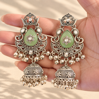 Cressida light green oxidised silver jhumka earrings with pastel green teardrop kundan-style stones photographed in hand