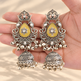 Cressida yellow oxidised silver kundan jhumka earrings with yellow teardrop stones and antique silver bell drops shown in hand