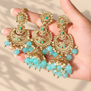 Dovey light blue polki jhumka earrings and maang tikka with white stones and blue bead drops held in hand