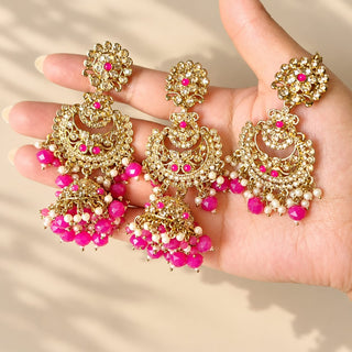 Dovey hot pink polki jhumka earrings and matching maang tikka with white stones and pink bead drops held in hand