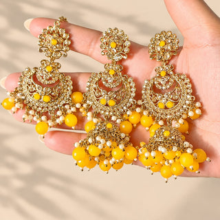 Dovey yellow polki jhumka earrings and maang tikka with pearl-like white and yellow beads held in hand