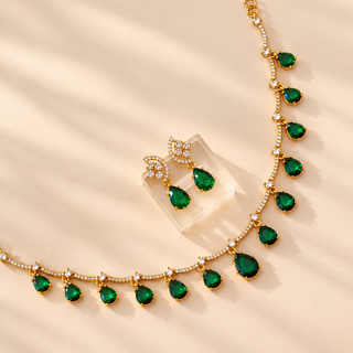 Imogen dark emerald green teardrop CZ necklace and matching 3 cm earrings closeup on beige background