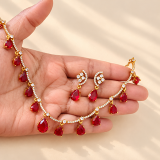 Imogen red artificial necklace and earrings set held in hand showing ruby red teardrop stones