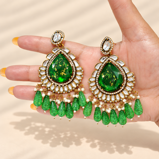 Lavinia dark green Indian imitation kundan chandelier earrings shown in hand with white pearl accents and green tassels