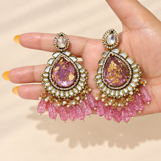 Lavinia purple kundan chandelier earrings 9 cm with white decorative stones and rose pink bead drops shown in hand