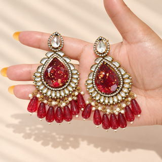 Lavinia 9 cm red kundan statement earrings held in hand with clear decorative stones and red teardrop bead tassels