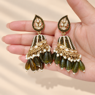 Ottoline green polki jhumka earrings shown in hand featuring olive green stones clear polki-style stones and white pearl beads
