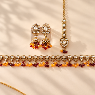 Raya dark red and orange polki necklace set with matching jhumka earrings and maang tikka gold finish