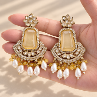 Rosamund yellow polki style earrings 7.5 cm long with gold finish and white pearl drops shown in hand