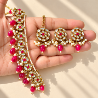 Winifred pink kundan necklace with matching 3 cm earrings and maang tikka close-up held in hand
