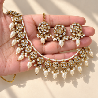 Winifred white kundan necklace with pearl drops matching earrings and maang tikka shown in hand